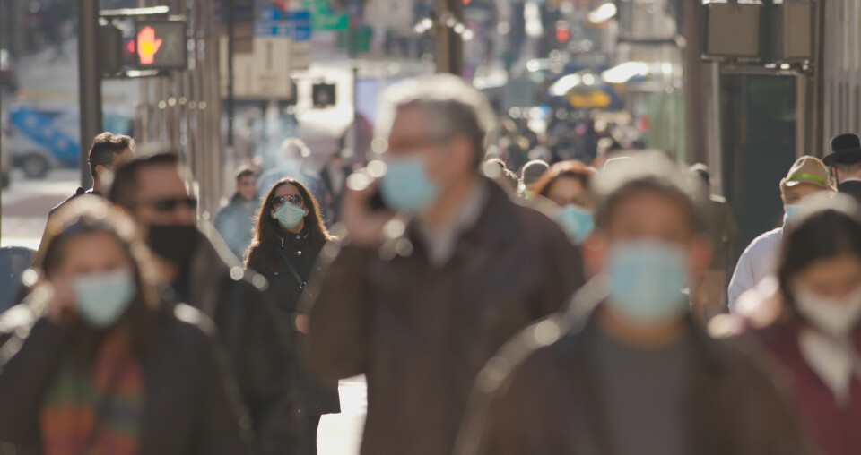 A blurred image of masked people walking in a crowded street