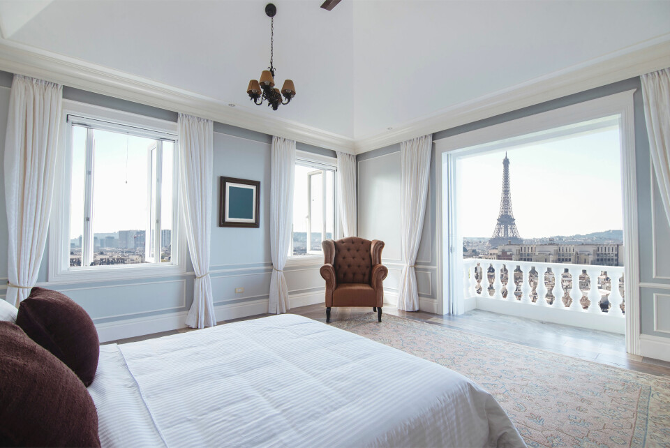A modern apartment bedroom looking out on a view of the Eiffel Tower in Paris