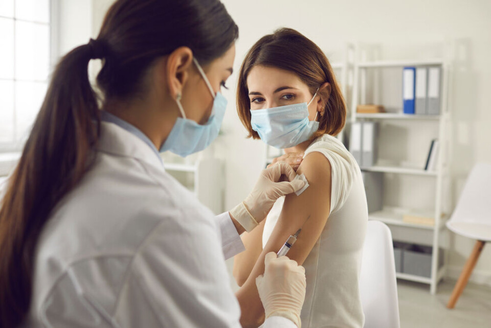 A younger woman receiving a Covid vaccine. ‘Make Covid vaccine mandatory for all’: French medical academies