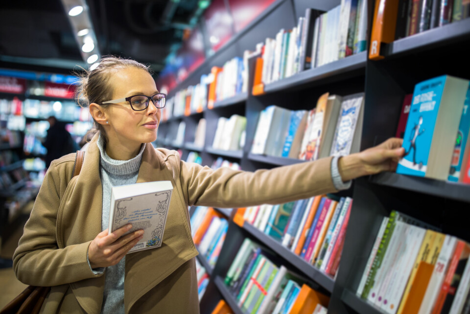 A woman chooses a book from a shelf in a bookshop