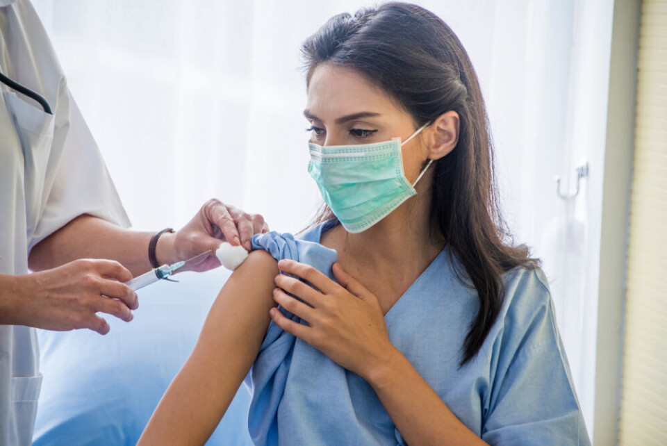 A nurse wearing blue scrubs and a medical mask receives a vaccination. French healthcare union calls for strike against mandatory vaccination