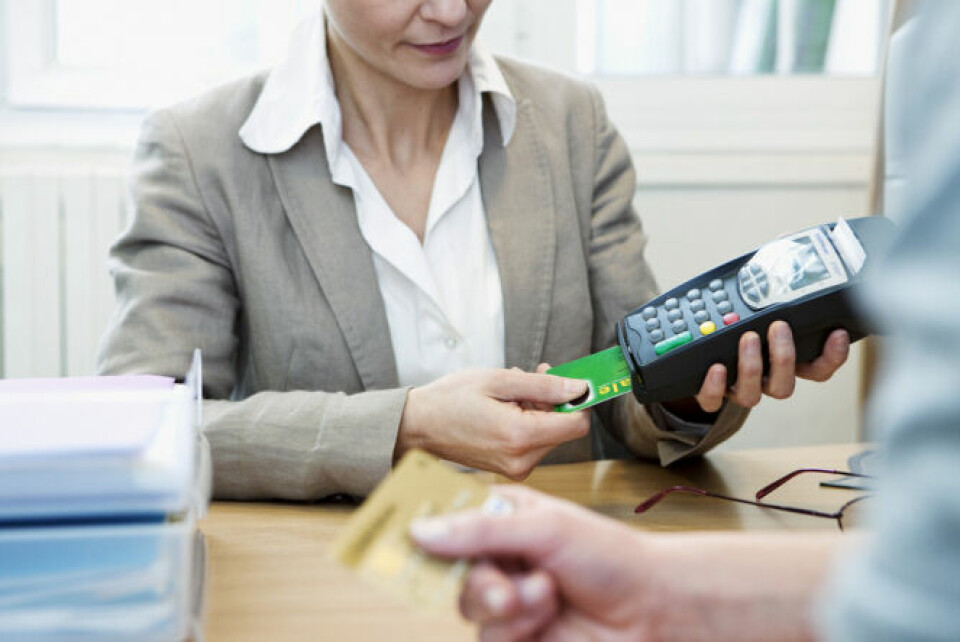 A woman inserting a carte vitale into a payment machine