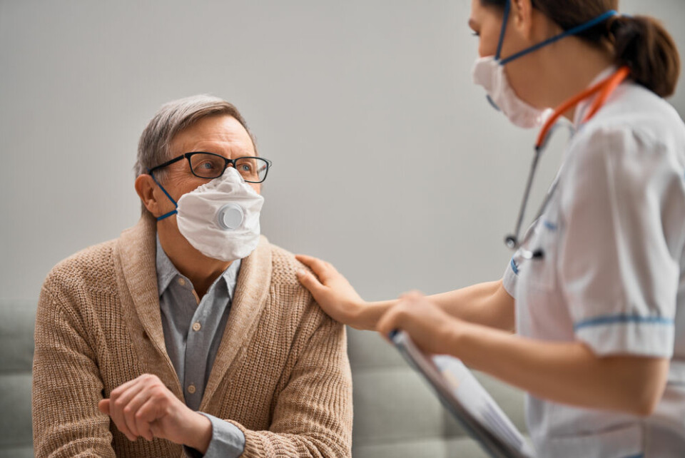 An older man wearing a mask being comforted by a nurse