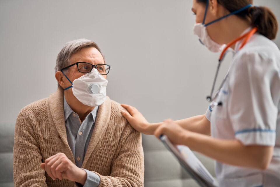 Yuganov Konstantin / Shutterstock An older man wearing a mask being comforted by a nurse