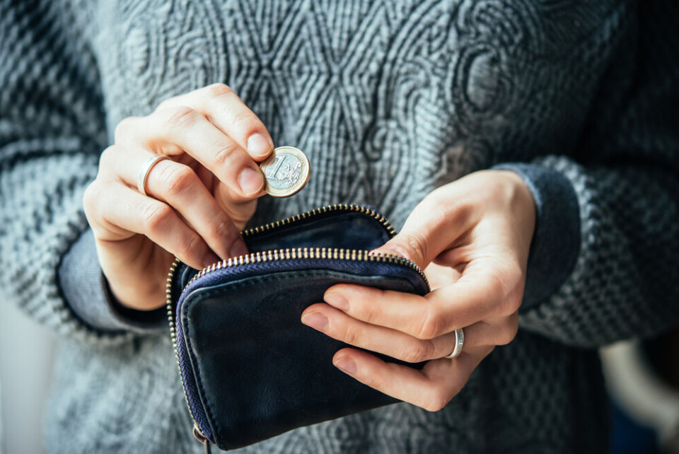 A view of someone holding a €1 coin from their wallet