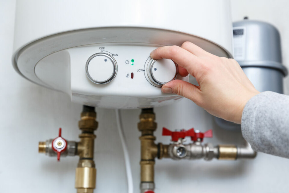 A woman adjusting a thermostat on a hot water heater