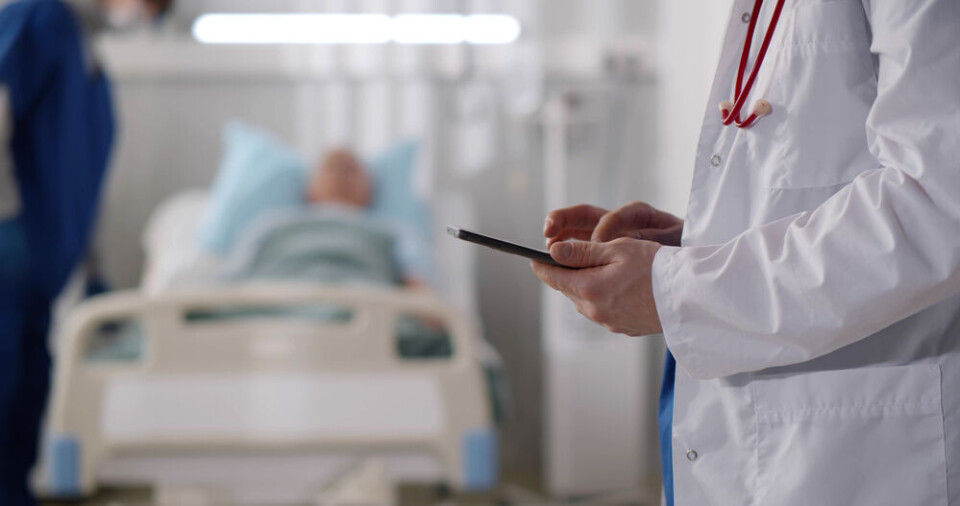 A view of doctors speaking at a hospital with a patient in the background