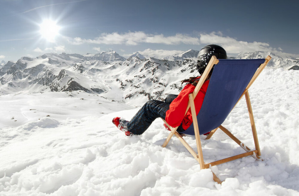 A view of a man sitting on a deckchair overlooking a view of high snowy mountains in France