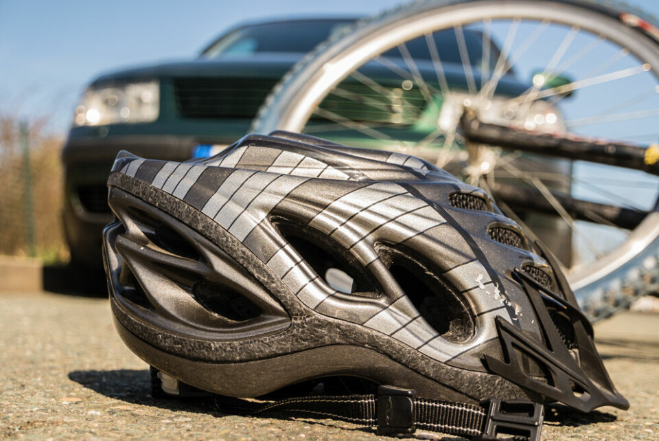 A view of a cycling helmet and bike on the ground next to a car