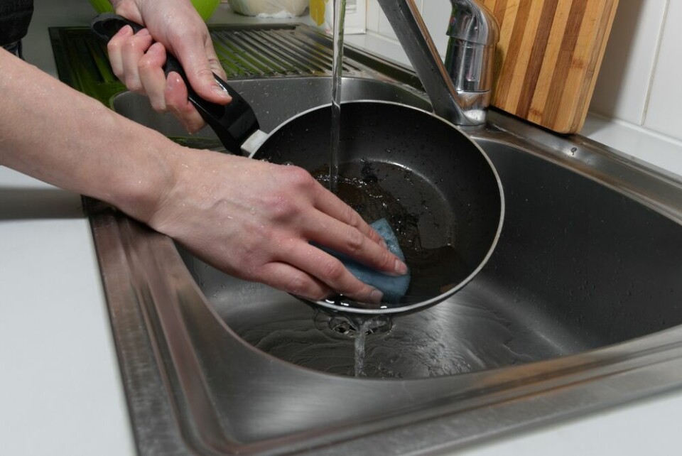 A view of someone cleaning a non-stick pan under running water