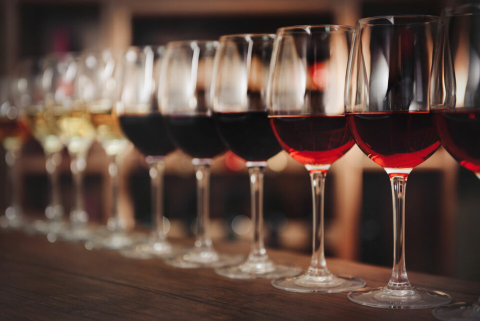 A view of wine glasses lined up on a bar with different coloured wine to show a ‘scale’