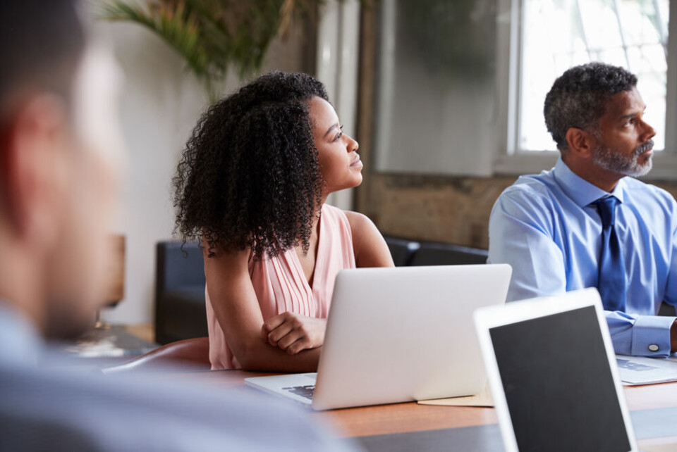 A view of a woman and man in the workplace, one with afro hair and the other with a beard and moustache