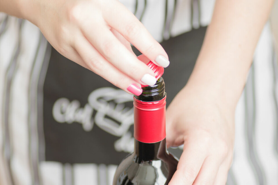 A view of a waitress opening a screw top bottle of wine in a restaurant