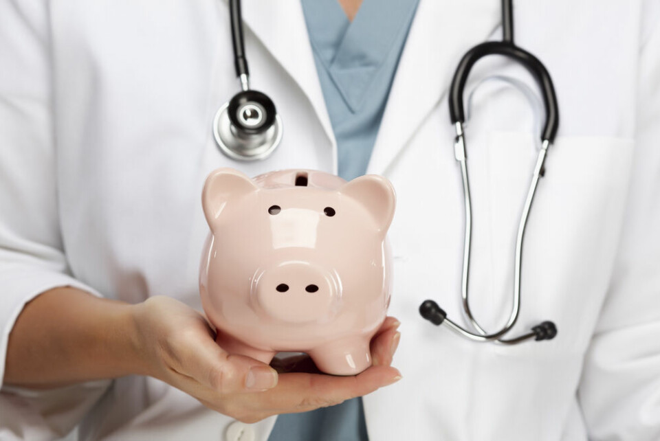 A doctor holding a piggy bank to show the cost of healthcare