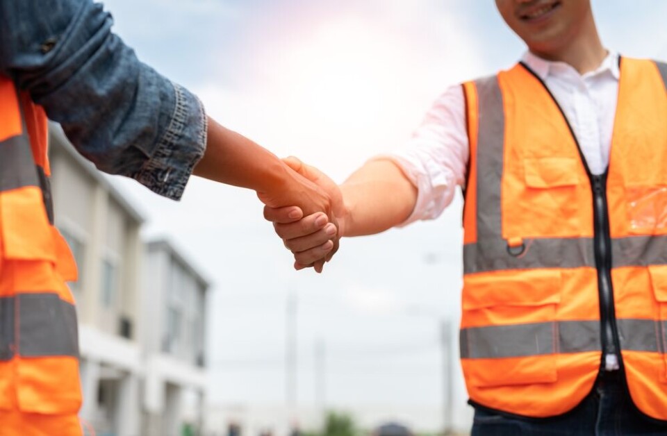 A view of two workers shaking hands on a construction job site