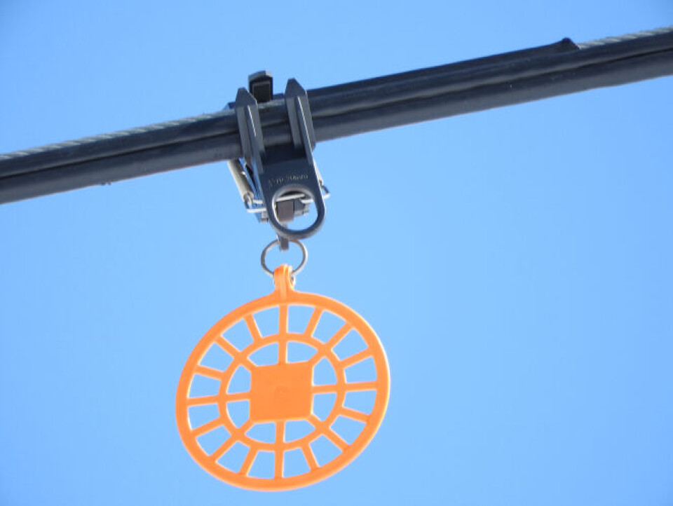 Brightly coloured disc hanging from a ski-lift cable