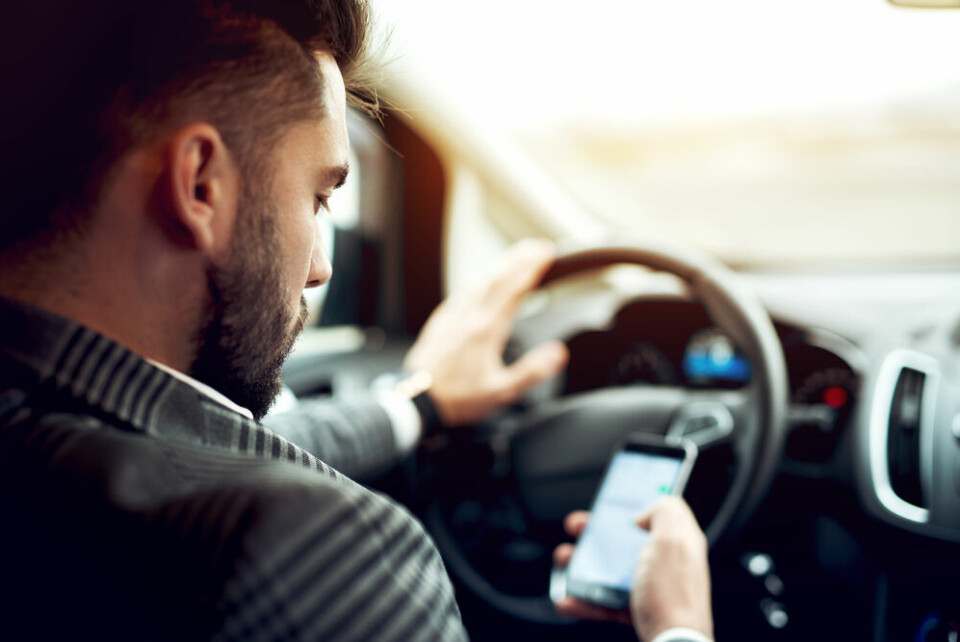 A man distracted while driving, looking at his phone