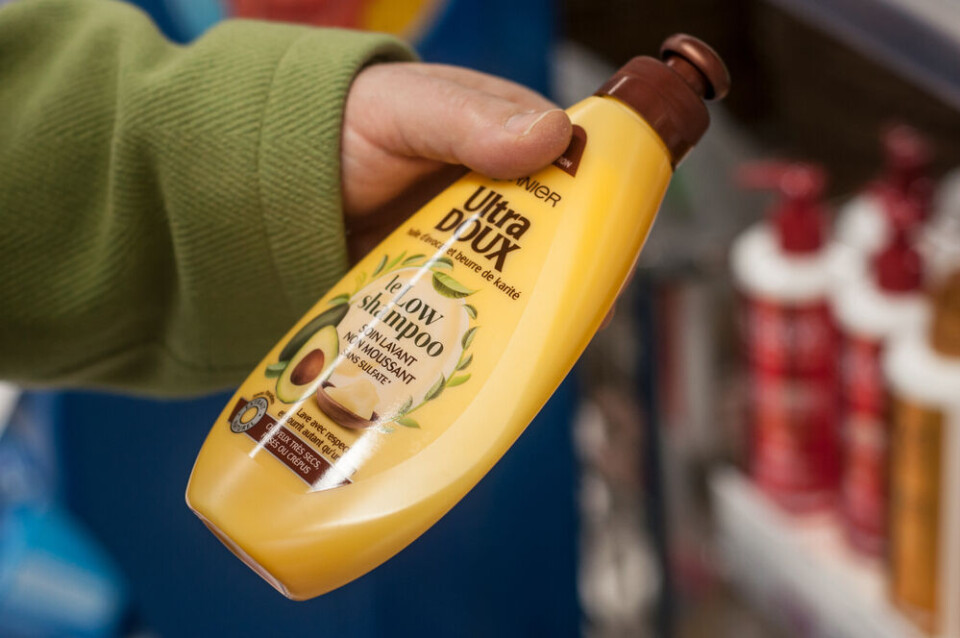 A woman looking at a shampoo bottle at a Super U supermarket