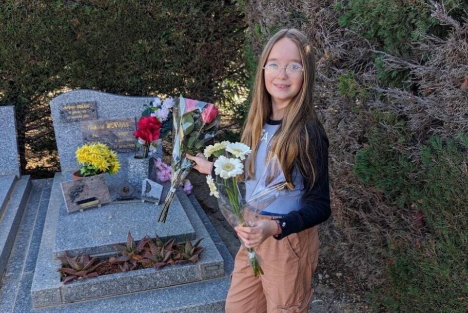 A view of Victoire placing cut flowers on a gravestone