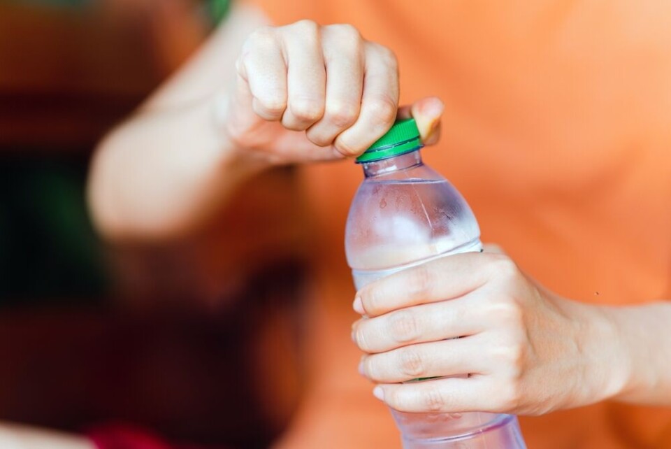 A woman opening a plastic bottle of water