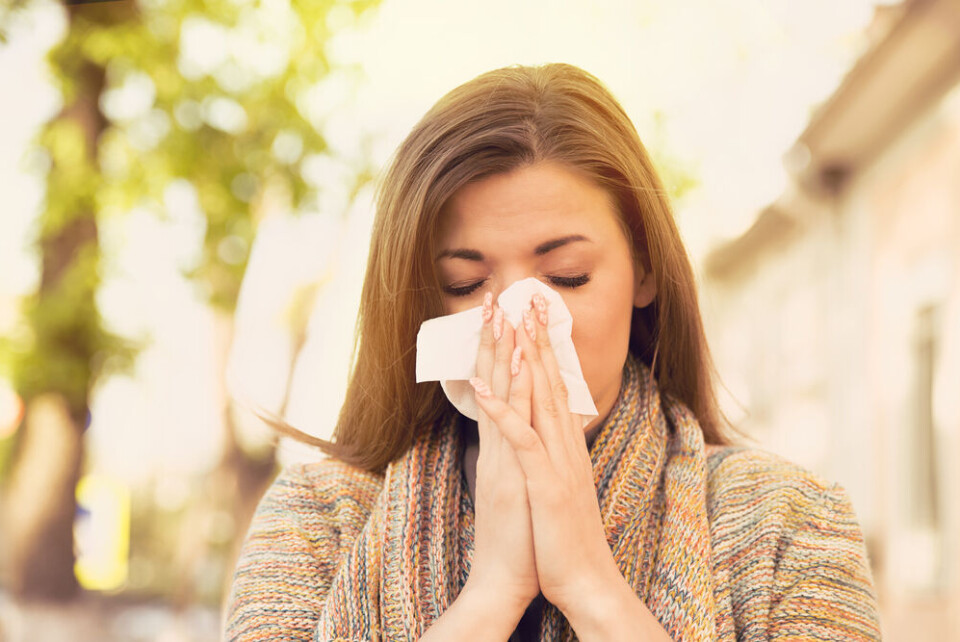 A view of a woman sneezing against a background of green vegetation