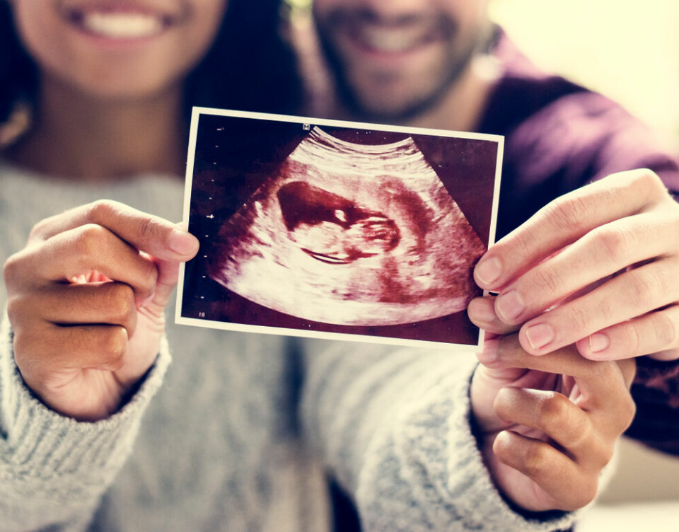 A view of a couple holding an ultrasound image of their baby