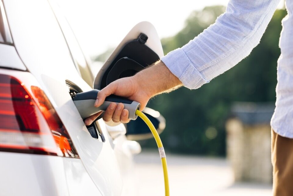 A view of a woman plugging in an electric car