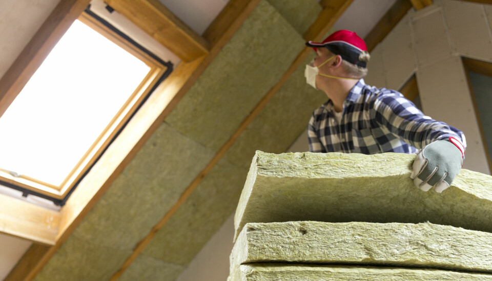 Man installing mineral wool loft insulation - wearing gloves and mask