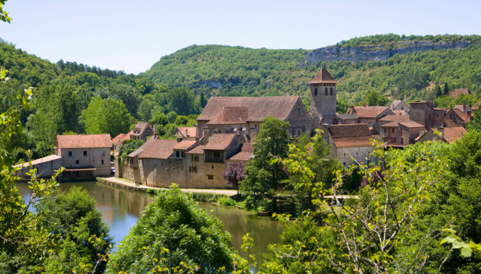 A view of Marcilhac-sur-Célé in a valley in Occitania, with water in front