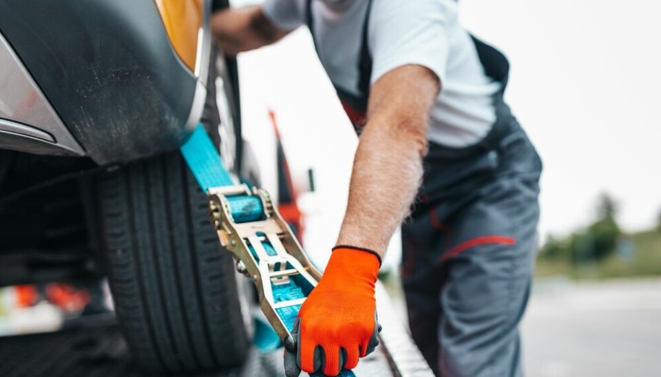 A view of a breakdown mechanic securing a car to a breakdown van
