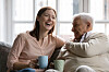 Two people laughing and holding a drink on a sofa in France.