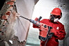 A builder and power tool get to work on a brick wall.