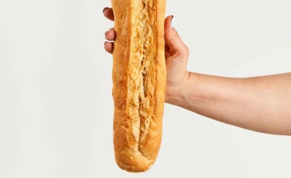 A view of someone holding a baguette with no view of the end