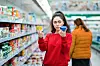 Woman in a supermarket holding up two products
