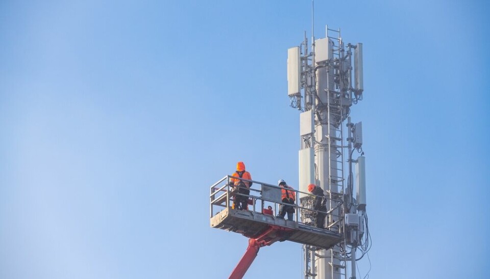 Engineers attach antenna high up 5G mast against blue sky in Normandy, France