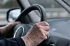A view of an elderly person’s hands driving a car