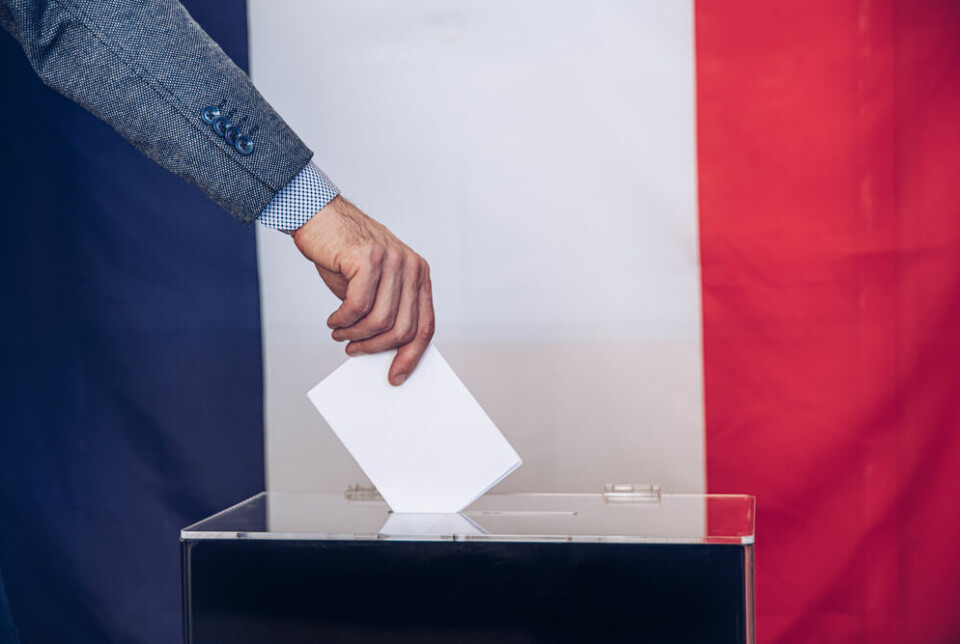 Man votes in front of a French flag