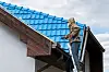 A man spray-painting a roof blue in France