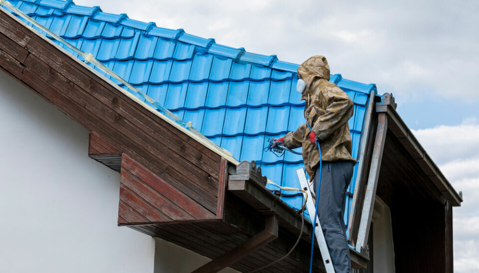 A man spray-painting a roof blue in France