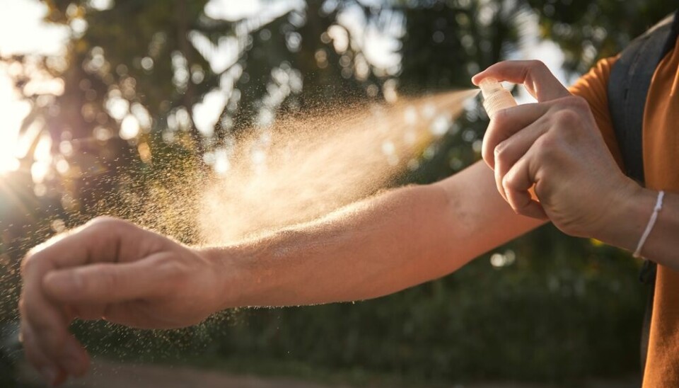 Man spraying his arm with mosquito repellent