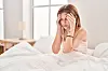 A woman in bed clutching her head