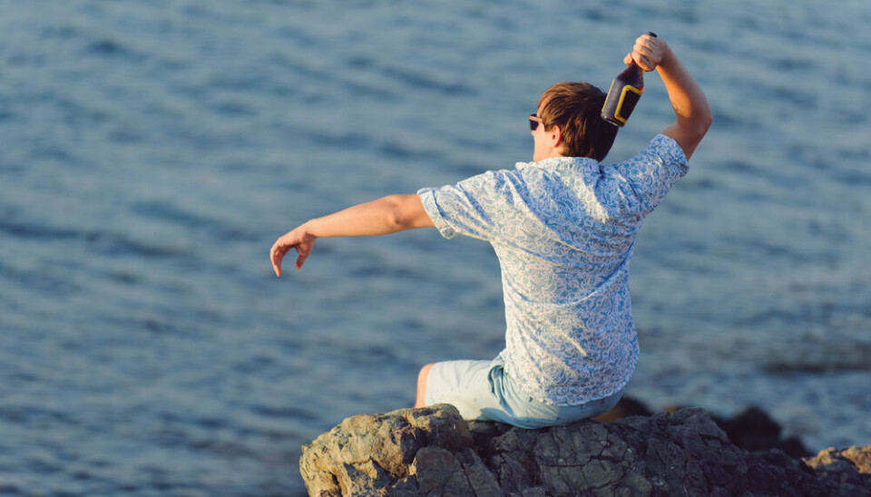 Andrei Zveaghintev/Shutterstock Man sitting on a rock throws a bottle out to sea