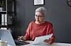 Woman at computer holding a document