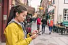 Woman,Using,Mobile,Phone,App,While,Walking,In,City,Street