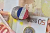 A view of some euro banknotes and coins, with one coloured with the French flag