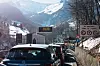 Cars waiting in a traffic jam below snow-covered mountains