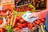 A view of someone holding euro notes against a background of fruit and veg