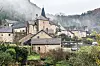 Stone buildings in a foggy valley surrounded by cliffs and trees