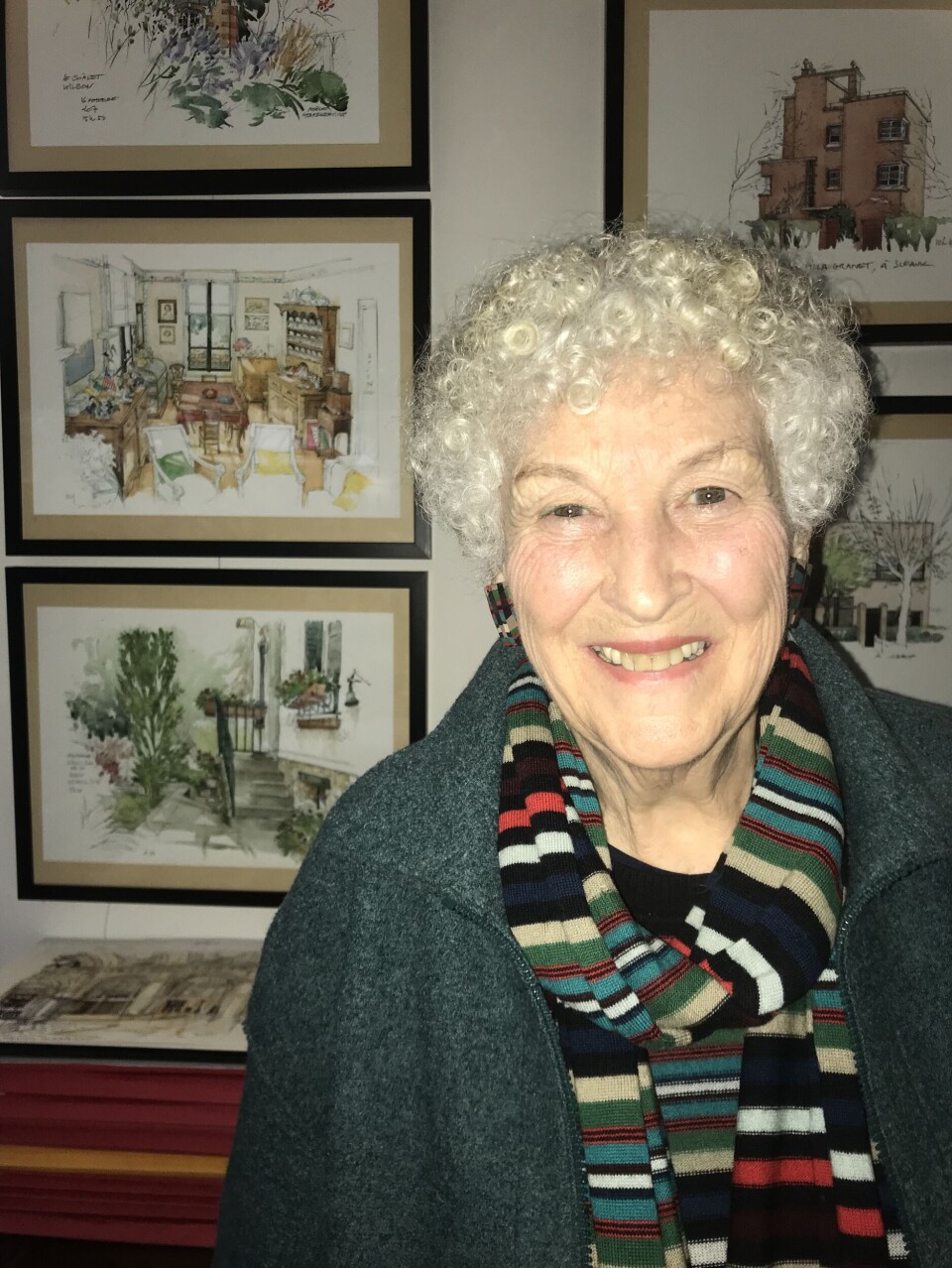 Théophile Larcher An elderly woman smiles before framed watercolour paintings