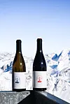 Bottle of red and white wine against snowy mountain backdrop